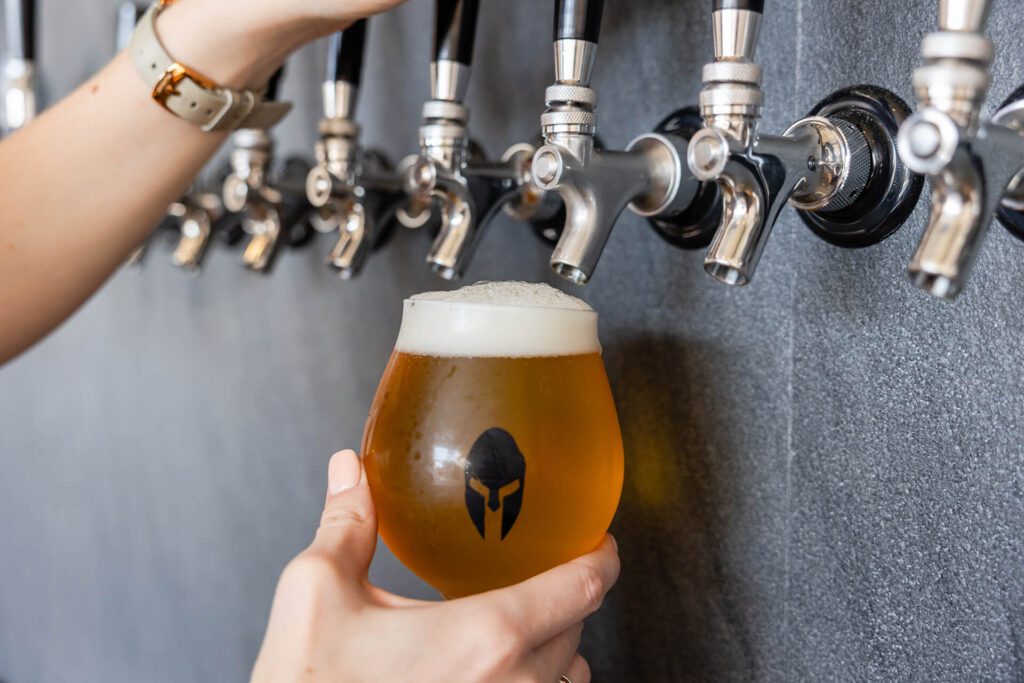 Pouring beer into glass with Spartan logo.